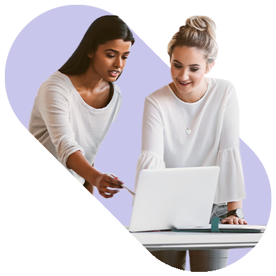 Two females leaning over a desk looking at a laptop