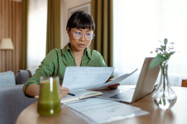 Lady looking at paperwork with computer