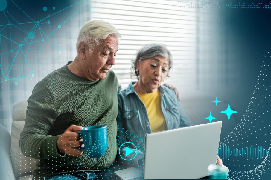 Elderly couple using a laptop, man holding a blue mug, with digital overlay.