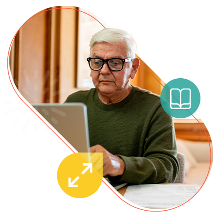 Older adult typing on a laptop, wearing glasses and a green sweater.