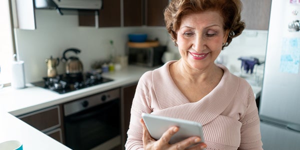 Smiling woman using a tablet in a modern kitchen.