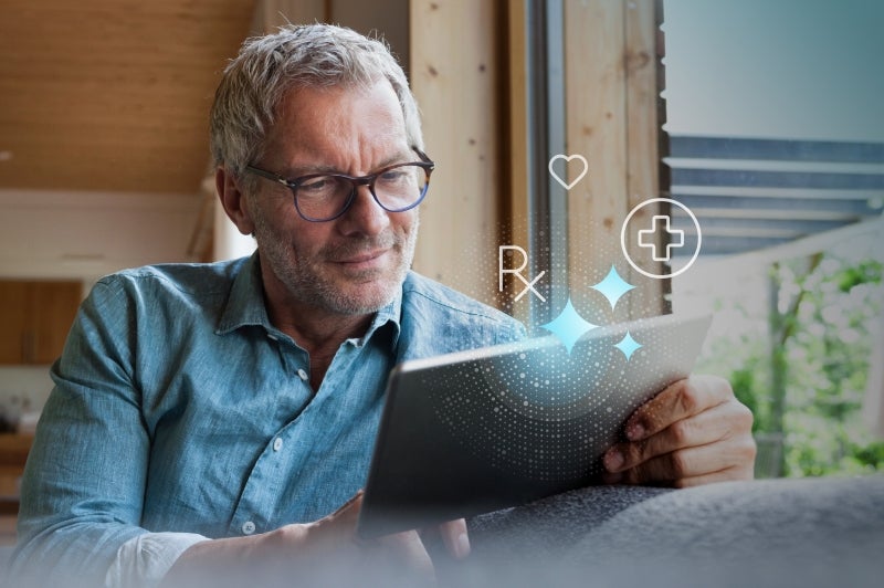 Man with glasses reading on a tablet, digital health icons around him.