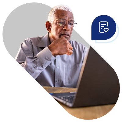 Elderly man thoughtfully using a laptop.