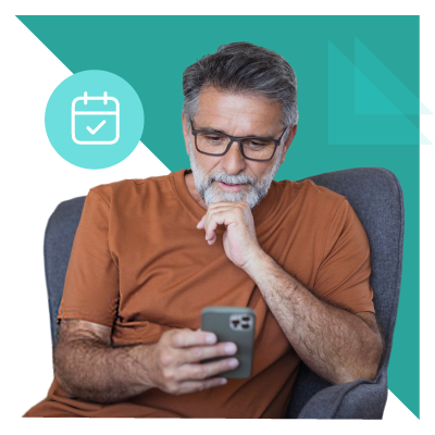 Older man in glasses sits on a chair, using a smartphone.